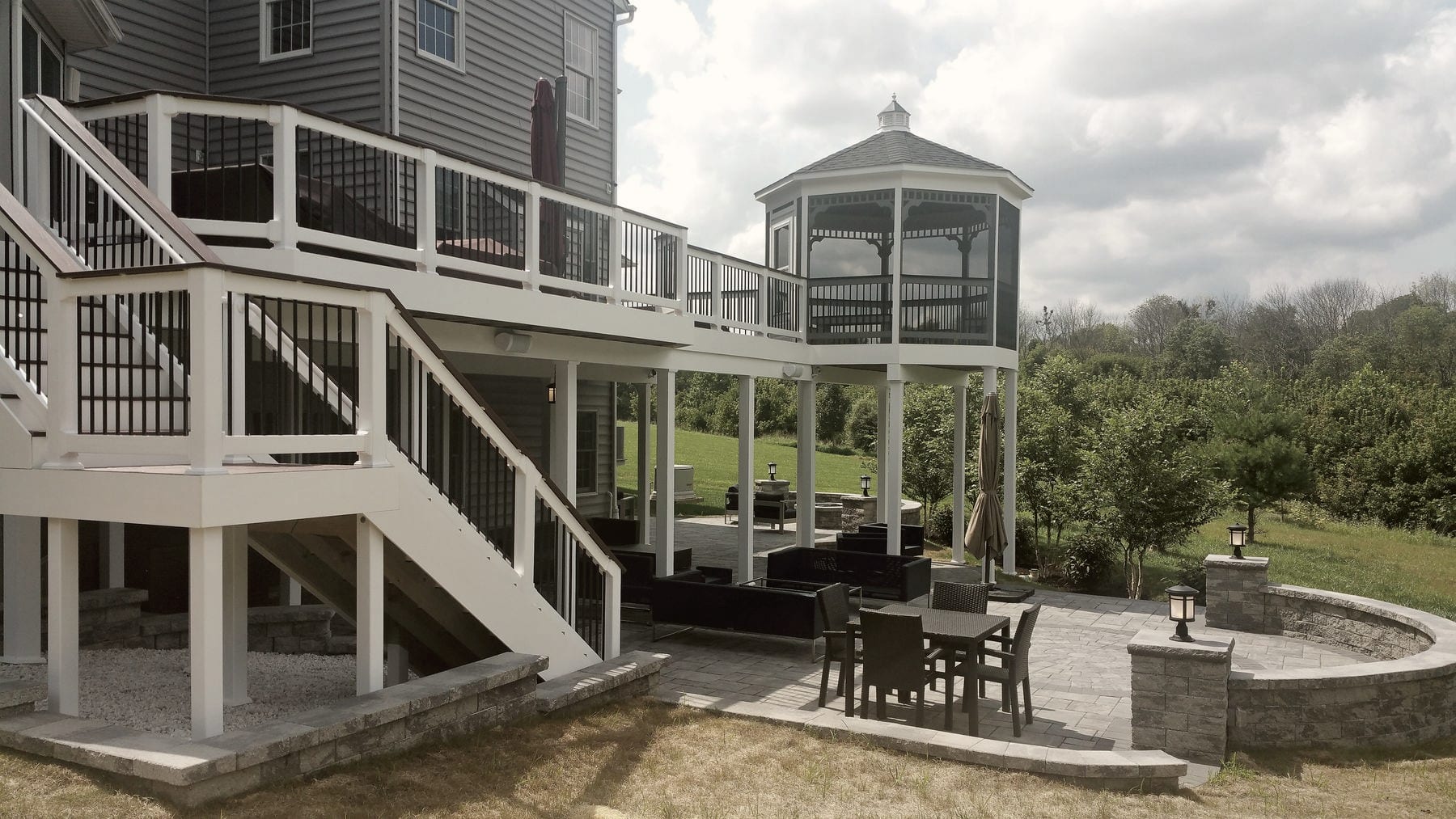 A deck with a screened gazebo and stairs down to the lawn