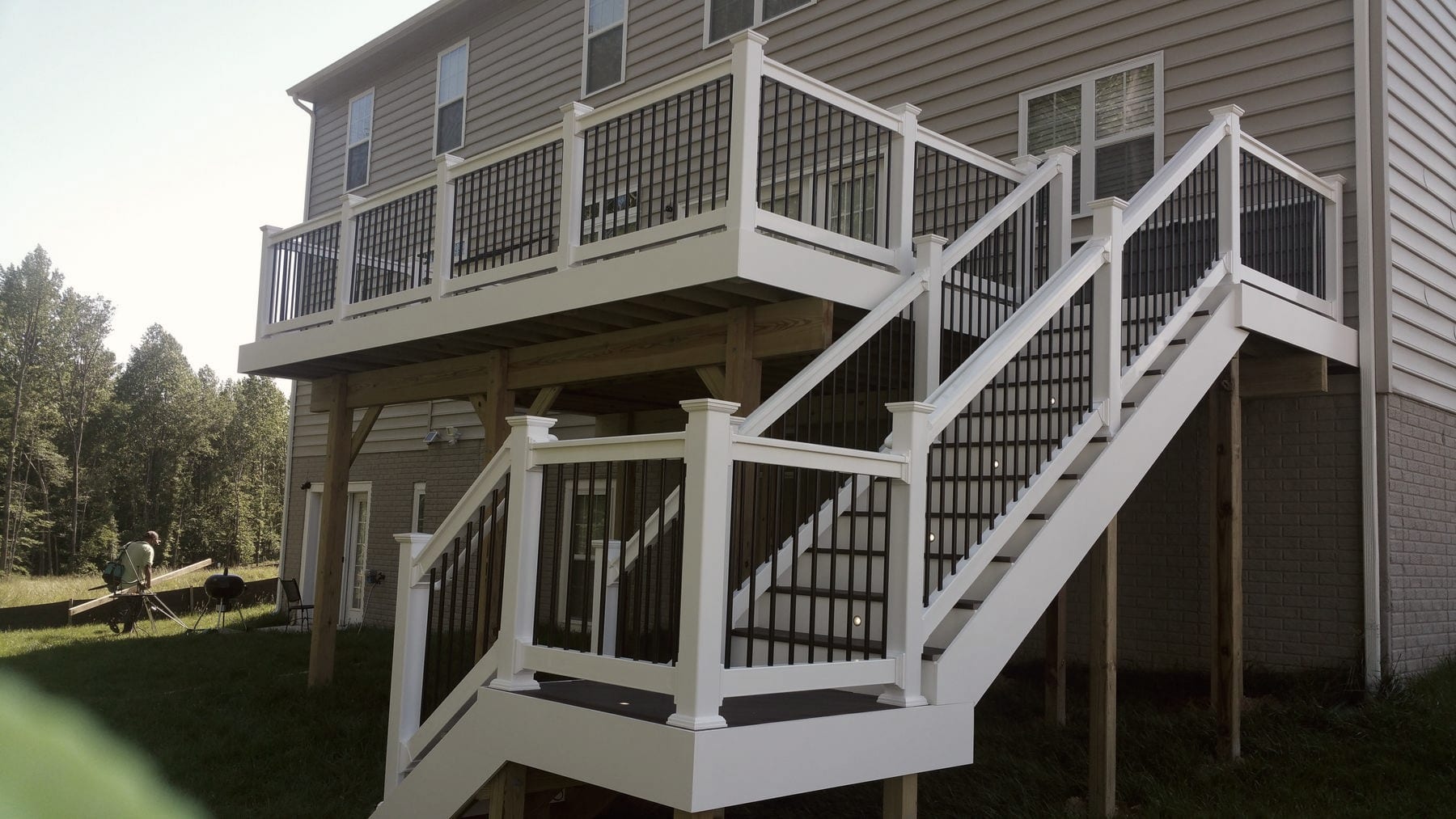 A finished deck with stairs and white railings above a lattice-screened understory