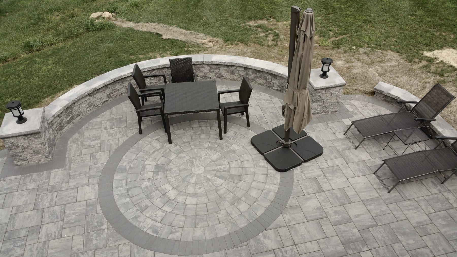 A paver patio with a fire pit, outdoor furniture and an umbrella