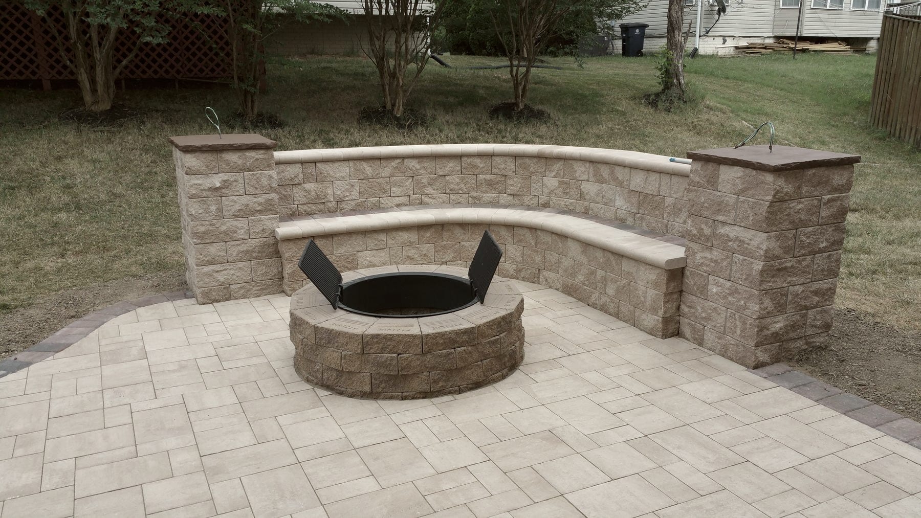 A stone fire pit set into a curved seat wall on a paver patio